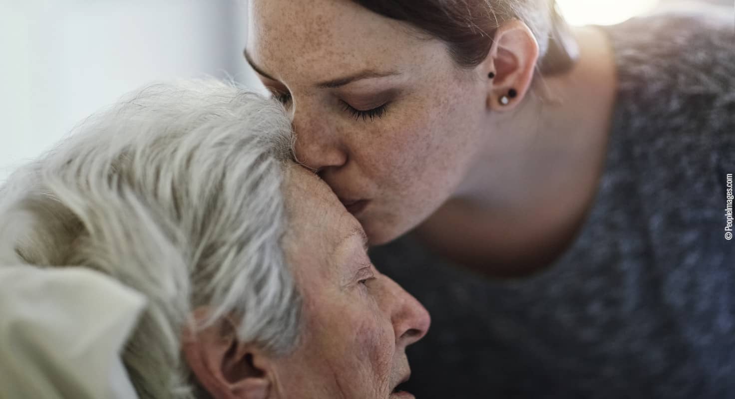 Una hija da un beso en la frente a su madre