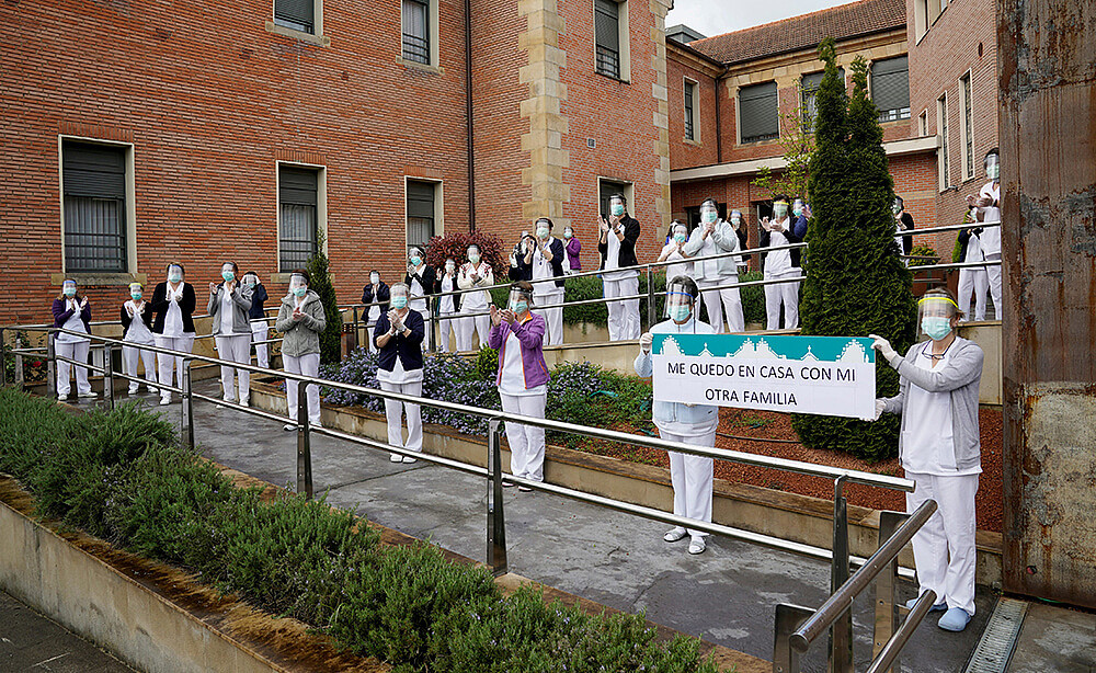 Treballadors i treballadores de la residència d'ancians Juan Calzada mostren una pancarta en la qual es llegeix "Ens quedem a casa amb la nostra...